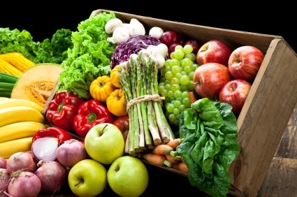 A vibrant assortment of fresh fruits and vegetables in a wooden crate.